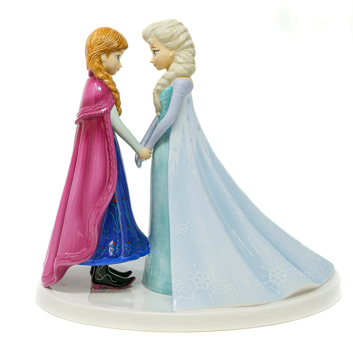 Two fine china princess figurines holding hands on white round base, pink and blue gowns