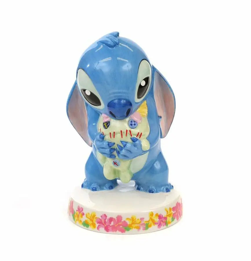 Blue Stitch-style bone china figurine holding a doll, on white floral base